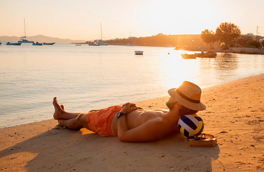 man relaxing and lying on the sand enjoying the sunset