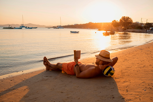 man relaxing and lying on the sand enjoying the sunset