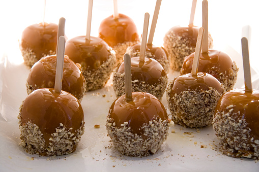 Caramel apples coated with almonds cooling down on a shelf in refrigerator
