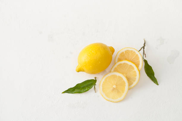 istock Lemon leaves and chopped lemon slices on a white concrete background. 899150786