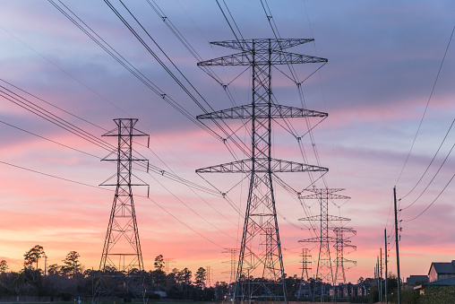 The silhouette of the high voltage power lines during sunset.