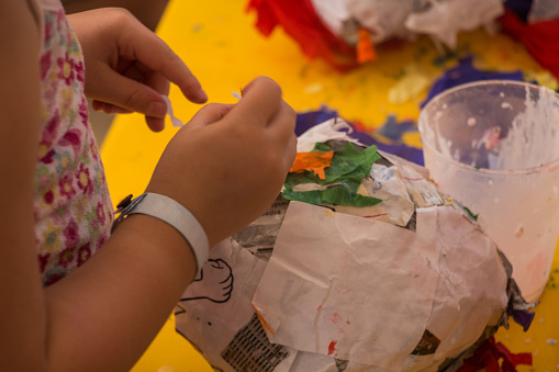 little girl making a piñata with recycled paper