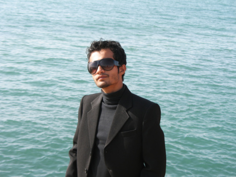 A man in formal wear standing by the sea.