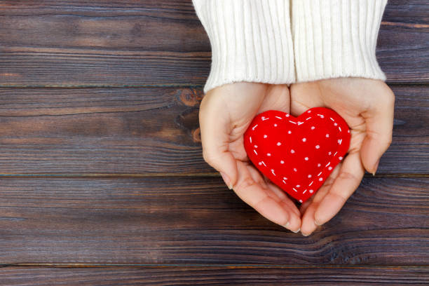 istock red heart in hands closeup on wooden background 899173414
