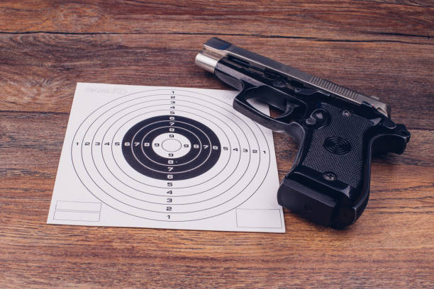 istock Target sign and a gun on a wooden table 899176948