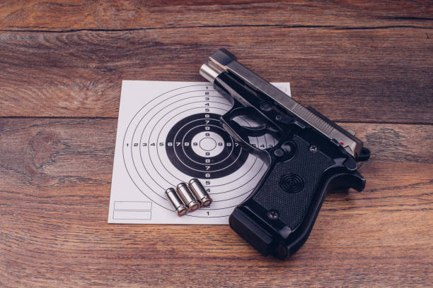istock Pistol, bullets and a target sign on a wooden table 899176996