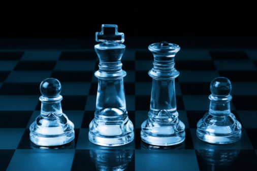 Pair of black and white chess pieces on chequered chessboard. End of game, checkmate. Strategy, risk management and leadership concept.