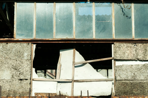 istock Damaged warehouse exterior wall with broken glass windows close up 899191284