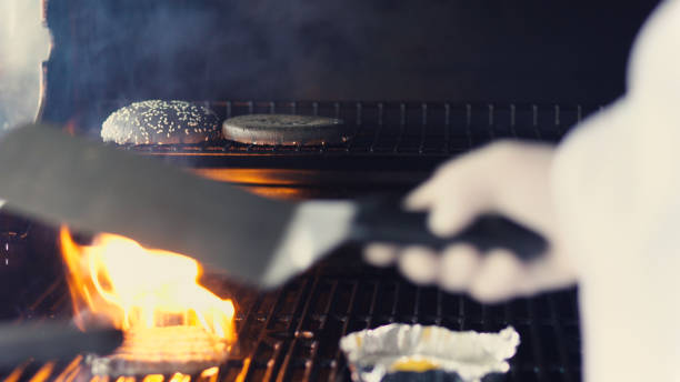 istock Closeup of chef preparing egg and cutlet for black burger on grill at restaurant kitchen indoors 899192128