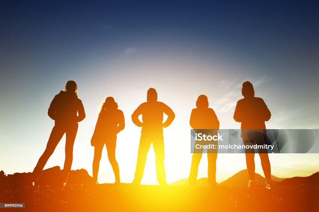 Grupo de cinco povos em silhuetas no pôr do sol - Foto de stock de Grupo de Pessoas royalty-free