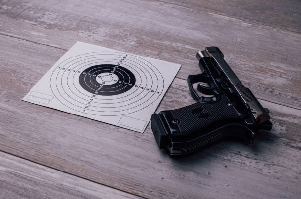 istock Pistol and target sign on a wooden table 899207306