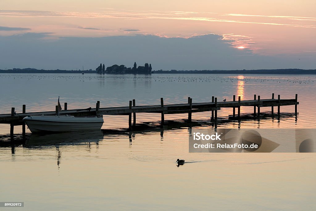 Barco en el embarcadero del lago con nubes al atardecer - Foto de stock de Agua libre de derechos