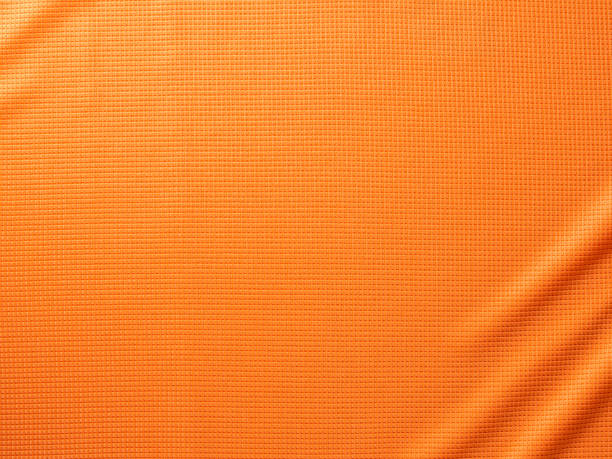 Sports Clothing Fabric Texture Background. Sports Fabric Full Frame Texture. Top View of Cloth Textile. Orange Football Team Uniform Close up. Clothing Background. Text Space textile industry stock pictures, royalty-free photos & images