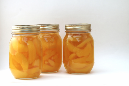 Peaches jam homemade glass pot with peach fruits on cutting board in white and blue background