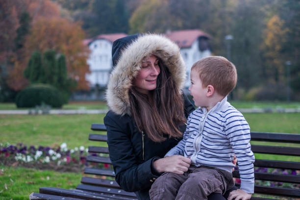 istock Mother sitting on bench and holding son in lap 899218170