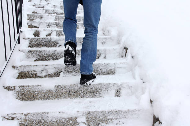 Risk of slipping when climbing stairs in winter Risk of slipping when climbing stairs in winter. A man goes up a snow-covered staircase flat shoe photos stock pictures, royalty-free photos & images