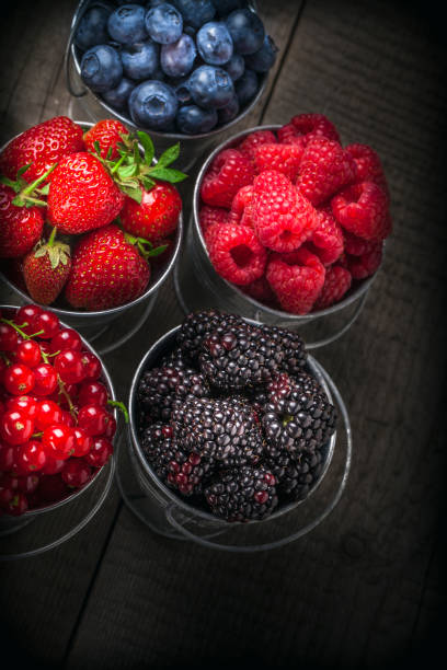 istock Berries in five tin cans overhead on dark wooden background 899225086