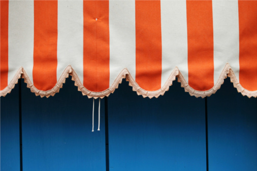 orange and white striped curtain made of rough linen on blue backgrounds, summer shelter