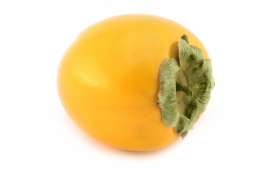 Fresh ripe persimmons in white bowl on cutting board and napkin on wooden table. Healthy vegan food concept. Top view.