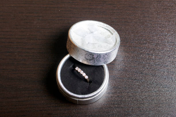 istock A gift to a loved one. An open silver box with a gold ring. On a dark background. 899259524
