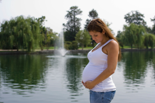 One woman, unrecognizable pregnant woman touching her belly.