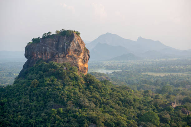 Sri Lanka's Sigiriya rock fortress viewed from Pidurangala Rock View of central Sri Lanka's famous Sigiriya rock fortress seen from Pidurangala Rock. People are visible walking up the steep staircase on the fortress. dambulla stock pictures, royalty-free photos & images