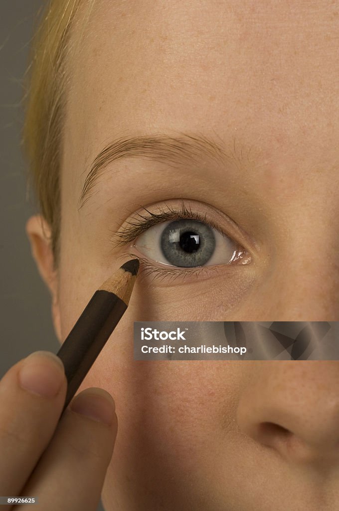 Pretty young woman using an eyeliner pencil  Adult Stock Photo