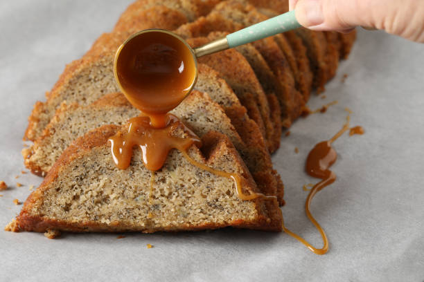 pouring rum caramel on banana bread - golden algae imagens e fotografias de stock