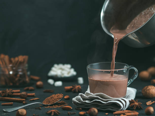 pouring tasty cocoa drink into mug on table - chocolate chocolate candy dark chocolate pouring imagens e fotografias de stock