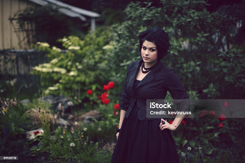 Mulher vestindo Roupas de escuro na frente de rosa com nos arbustos - Royalty-free Adulto Foto de stock
