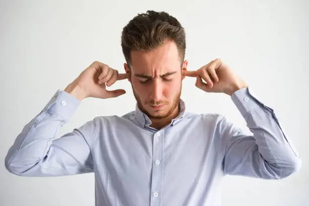 Photo of Irritated businessman plugging ears with fingers