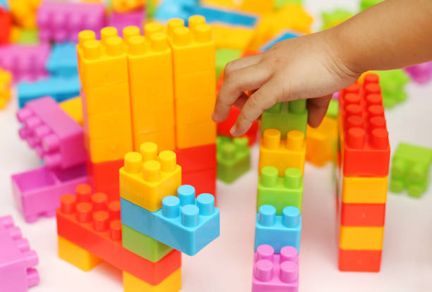 istock Child's hand building plastic toy blocks with blurred background 899300634