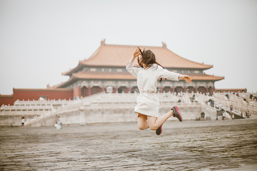 A girl jumps high up in the forbidden city in Beijing,China.