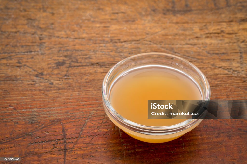 unfiltered, raw apple cider vinegar unfiltered, raw apple cider vinegar with mother  - a small glass bowl against rustic wood with a copy space Apple Cider Vinegar Stock Photo