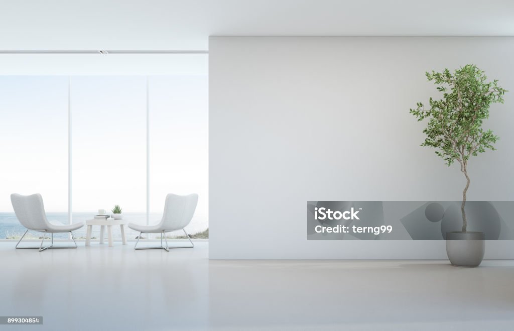 Planta de interior en el piso blanco con fondo de muro de hormigón vacía, salón y mesa de centro junto a la ventana de cristal en mar vista salón de hotel o casa de playa de lujo moderno - Foto de stock de Clínica médica libre de derechos