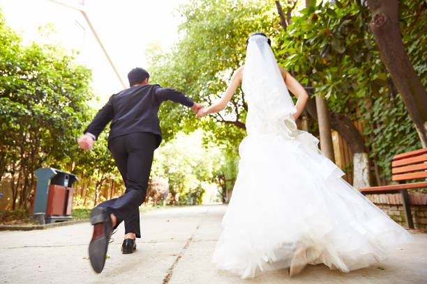 running newlywed asian couple asian wedding couple running on street celebrating marriage. chinese wedding dress stock pictures, royalty-free photos & images
