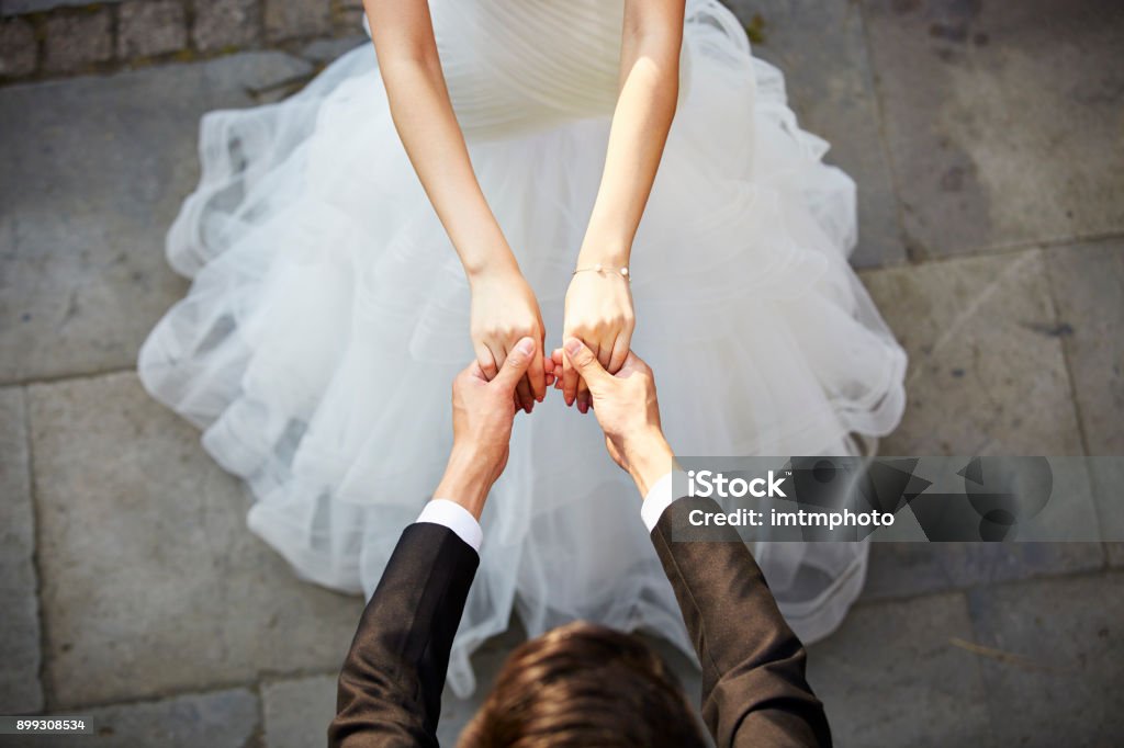 young asian adults dancing in wedding dress young asian newlywed couple wearing wedding dress dancing in open ground, high angle view. Wedding Stock Photo