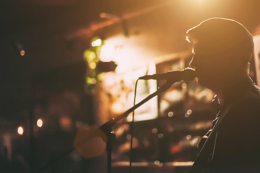 A male singer on a stage performing with guitar at a bar.