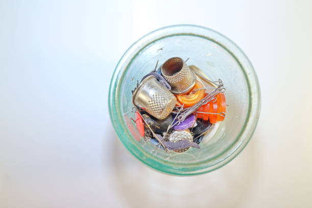 An old spool of blue thread with a needle inserted, placed on a red fabric background