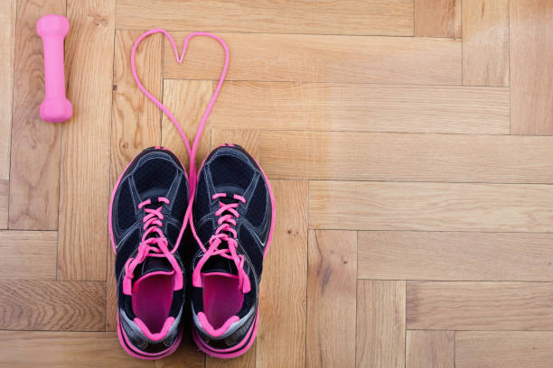 Fun image of everyday sneakers with their laces forming a heart shape. Shallow depth of field keeps the focus on the heart shape. Useful image for fitness, footwear, or jogging.