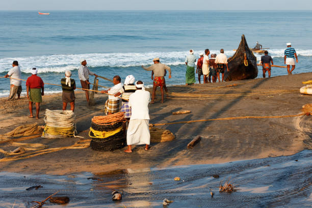 Varkala, India - February 09, 2016: Fishing net with fishermen on backside the boat. Odayam beach, Varkala, India