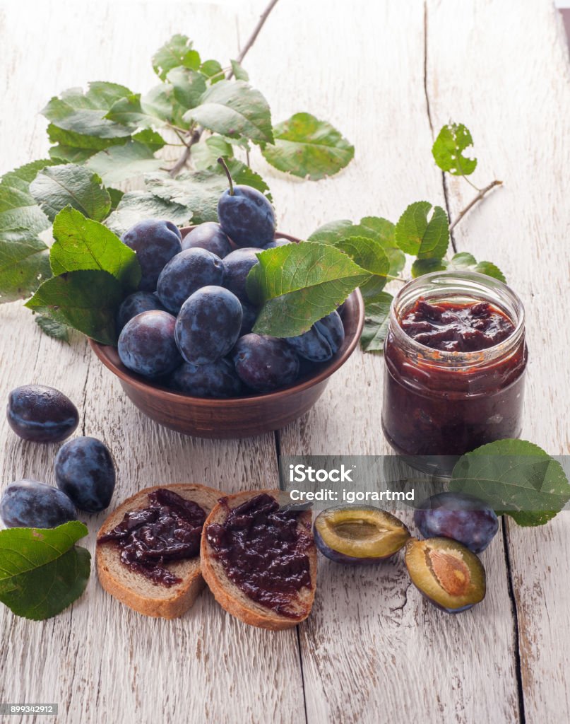 Plums and jam Fresh plums with homemade jam on wooden table Blue Stock Photo