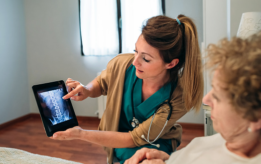 Female doctor showing to female senior patient an x-ray on the tablet