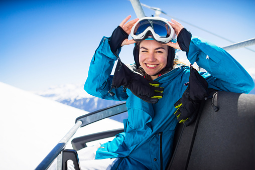 young  snowboarder woman smiling at ski lift (ski resort)