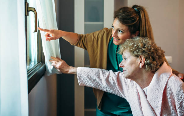 istock Caregiver showing the view through the window to elderly patient 899348084