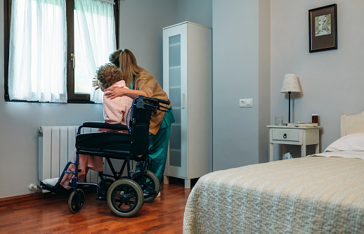 Caregiver showing the view through the window to an elderly patient in a wheelchair
