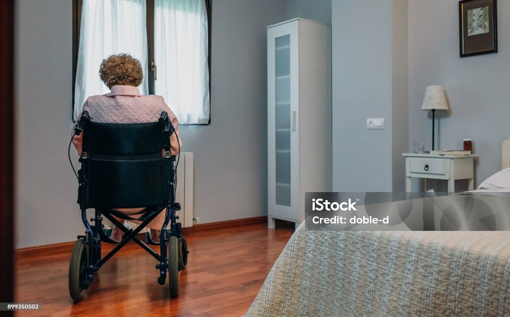 Senior woman in a wheelchair alone Senior woman in a wheelchair alone in a room Senior Adult Stock Photo