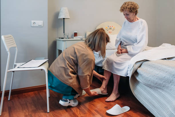 carer wearing slippers to elderly patient - social worker assistance home caregiver community outreach imagens e fotografias de stock