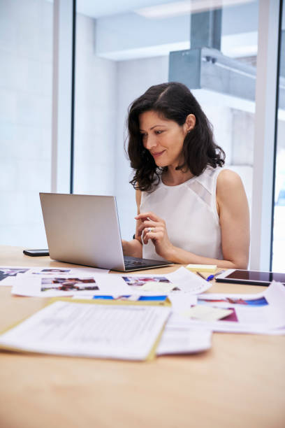 istock Woman in creative media office using laptop, vertical 899352688