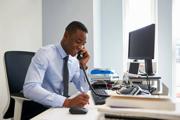 istock Young black businessman using the phone at his office desk 899355186